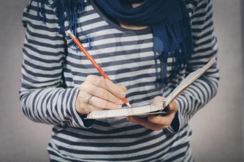 young woman writes something in a notebook