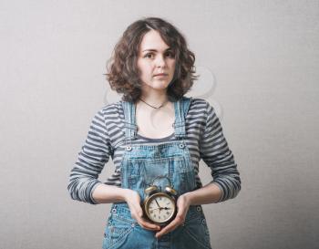 beautiful woman holding alarm clock in hand, dressed in a suit