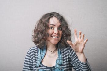 Woman playfully scared hand grimace. Gray background