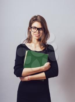 Young beautiful Girl with glasses reading a  big green book