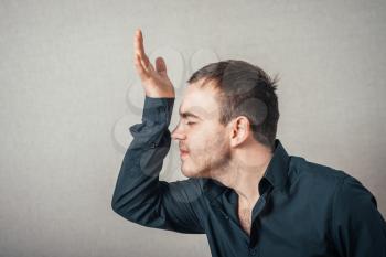 Man thinks upset with his hand near his head. On a gray background.