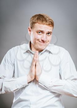 Closeup portrait of desperate young man showing clasped hands, pretty please with sugar on top, isolated on white background. Positive emotion facial expression feelings, signs symbols, body language.