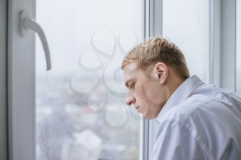 Young businessman looking out of a window and thinking