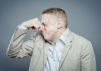 Young business man close up over gray background. Grabbing his nose with his fingers