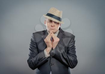 Closeup portrait desperate young man  in hat showing clasped hands, pretty please  on top isolated grey wall background. Human emotion facial expression feelings, signs symbols body language