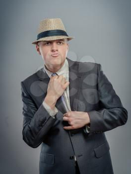 businessman in hat straightens tie