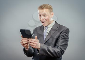 Successful businessman standing using a tablet to access the internet as he leans 
