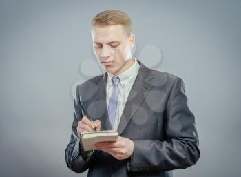 Businessman in suit writing on empty notepad (notebook)