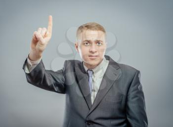 Handsome young business man happy smile point finger up to empty copy space, businessman showing pointing up, concept of advertisement product, wear elegant suit and tie