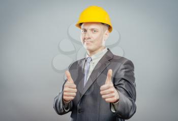 young man in a yellow hard hat showing thumb up