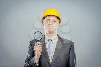 engineer man in helmet with a magnifying glass, focus on the glass