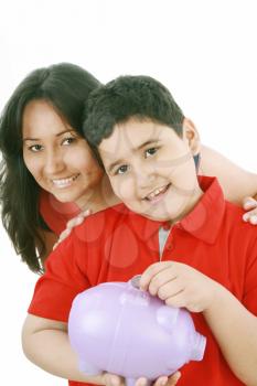 Portrait of a caring mother teaching her son to save money in piggybank over white background 
