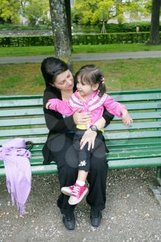 Portrait of smiling mother and little daughter hugging in the park 