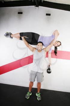 Handsome man lifting a beautiful woman at the gym 