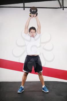 Young man doing kettlebell workout on gym