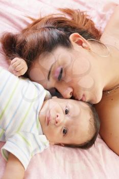 Hispanic woman kissing newborn 