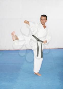 Man in a kimono hits with foot and hand.  Karate Concept