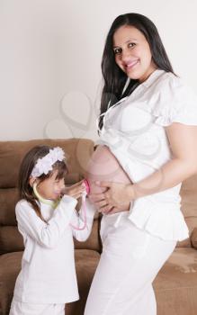 girl examining pregnant mother's tummy 