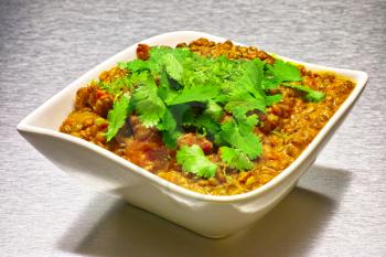 Moong Dahl, indian vegetarian lentil soup, in white bowl. Aluminium background.