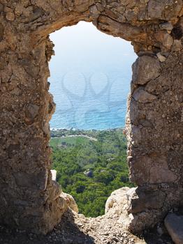 Rhodes island coast through wall opening  of Monolithos castle. Greece.