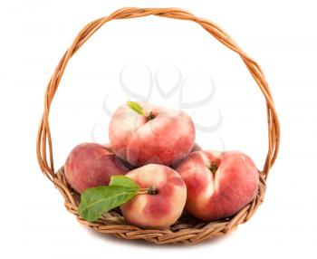 Paraguayos flat peaches with green leaves in wicker basket isolated on white