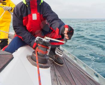 Man holding winch with rope on sailing boat
