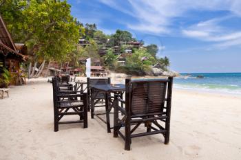 Chairs and table on the sand beach with blue sky. Koh Phangan, Thailand
