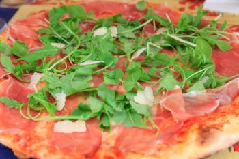 Italian pizza with parmesan, rucola and prosciutto closeup view
