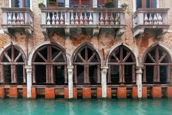 Venice channel and vintage grunge building with columns and arcs
