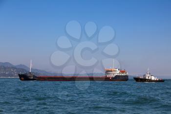Bulk-carrier ship and tugboat moving in the sea
