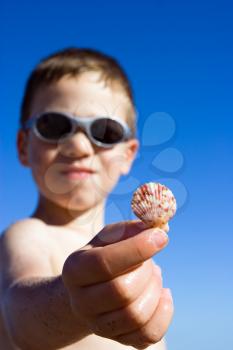A young child on the beach showing shell