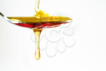 honey pouring in a spoon on white background