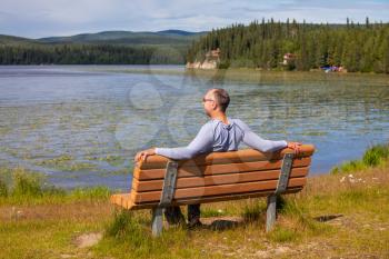 Royalty Free Photo of a Man Sitting on a Bench Beside a Lake