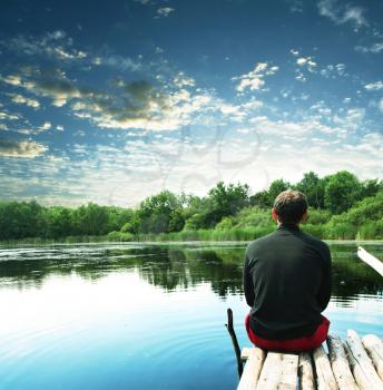 Royalty Free Photo of a Man Sitting at a Lake