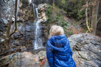Little girl standing in front of waterfall. Happy emotion concept.