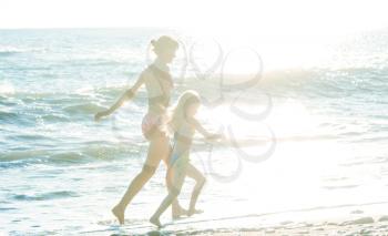 Family on the beach on sunset. Mother and daughter running together.