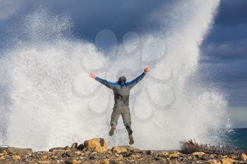 Man jumping in dramatic storm waves