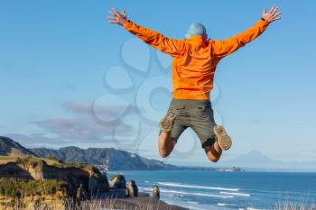Jumping man on ocean coast, New Zealand