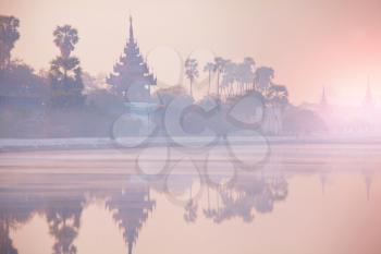 Ancient brown brick Palace wall with reflection in the canal surrounding the Mandalay palace located in Mandalay, Burma (Myanmar) at sunrise