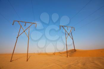 Electrical power lines on pylons stretch in sandy Namib desert, Namibia, Africa