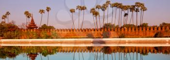 Ancient brown brick Palace wall with reflection in the canal surrounding the Mandalay palace located in Mandalay, Burma (Myanmar) at sunrise