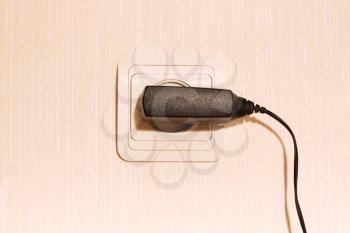 Beige wall plug with a cable for a mobile phone