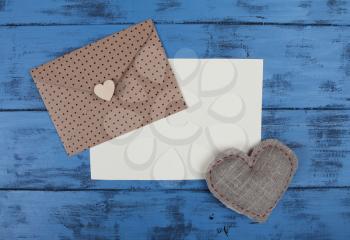 Envelope, heart and blank paper sheet on blue wooden background