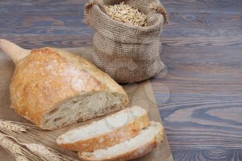 Fresh baked wheaten bread on wooden background with grains