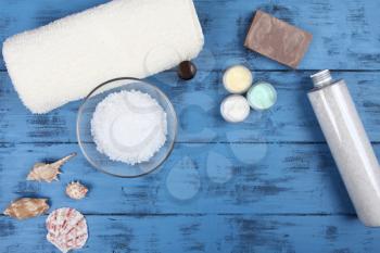 Aromatherapy spa set with natural soap, bath salt and towel on blue wooden background