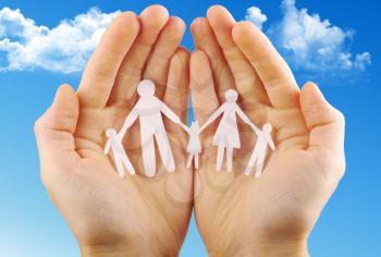 Paper family in hands isolated on blue sky
