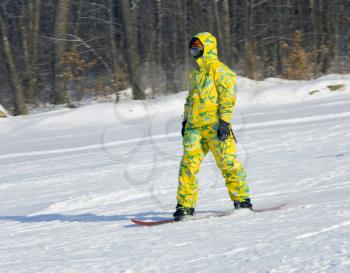 Snowboarder in a yellow suit going from mountain on against wood