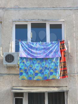 The clothes dry at a white window near to the conditioner