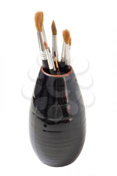 Vase with brushes of the artist on a white background