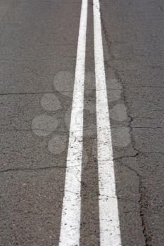 Texture of an asphalt road with a top view of a double white stripe